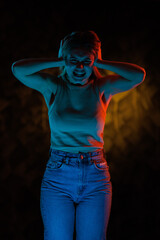 Young girl posing and moving in a black studio with colored light	