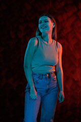 Young girl posing and moving in a black studio with colored light	