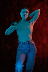 Young girl posing and moving in a black studio with colored light	