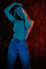 Young girl posing and moving in a black studio with colored light	