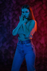 Young girl posing and moving in a black studio with colored light	