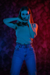 Young girl posing and moving in a black studio with colored light	