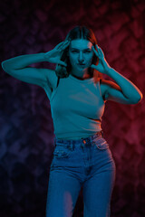 Young girl posing and moving in a black studio with colored light	