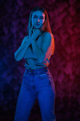 Young girl posing and moving in a black studio with colored light	