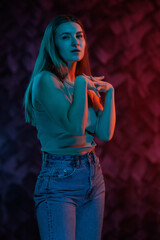 Young girl posing and moving in a black studio with colored light	