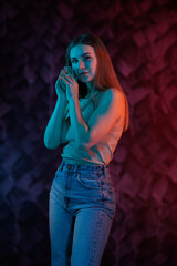 Young girl posing and moving in a black studio with colored light	
