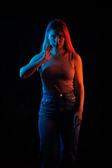 Young girl posing and moving in a black studio with colored light	