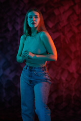 Young girl posing and moving in a black studio with colored light	