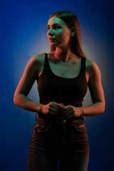 Young girl posing and moving in a black studio with colored light	