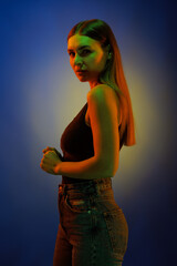 Young girl posing and moving in a black studio with colored light	