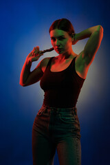 Young girl posing and moving in a black studio with colored light	