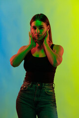 Young girl posing and moving in a black studio with colored light	
