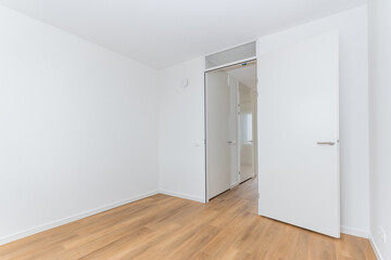 interior empty unfurnished basic room in modern new build residential smart house. Plain white walls and wood effect vinyl flooring make blank canvas open door to corridor landing