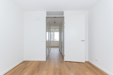 interior empty unfurnished basic room in modern new build residential smart house. Plain white walls and wood effect vinyl flooring make blank canvas open door to corridor landing
