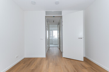 interior unfurnished empty basic stairway corridor landing to bathroom in modern new build residential smart house. Glass window view. Plain white walls and wood effect vinyl flooring blank canvas