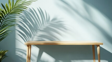 Fototapeta premium Wooden table with palm leaf shadow on light blue wall.