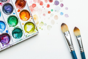 Fototapeta premium Paint brushes and colorful watercolor paint splashes on white background