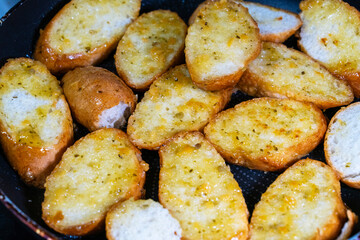 baking baguette slices with garlic sauce on the frying pan
