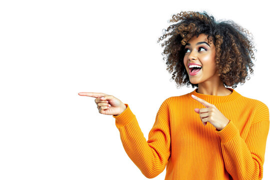 Smiling woman in an orange sweater pointing to the left with both hands, excited expression, curly hair, isolated on white background. Concept of advertisement. Ai generative
