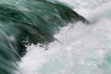 Cascade on rapid river close up, motion blur and spraying water, abstract landscape