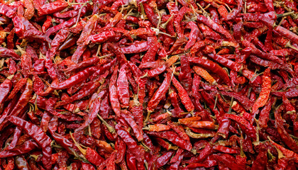 Fototapeta premium Background filled with dried red chili peppers, showcasing their wrinkled texture and vibrant red color. Perfect for spicy, Mexican, or gourmet food concepts. Texture, background.