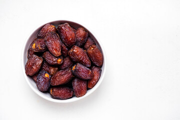 Organic sun dried royal dates in bowl on white background, top view