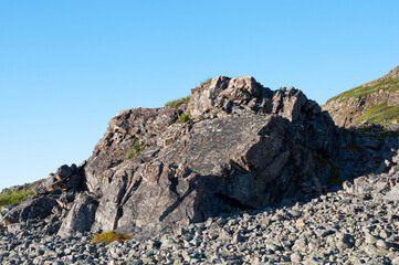 Large rock on mountainside against blue sky. Rybachy peninsula, Murmansk region, Russia