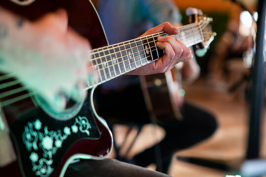 Guitarrista tocando la guitarra en un concierto ac&uacute;stico con la mano enfocada en los trastes