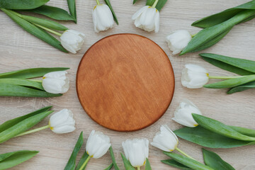 White tulips arranged around a wooden circle on a light wooden surface, Round wooden sign mock up