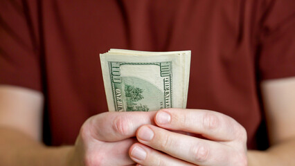 A person grips a handful of cash, indicating readiness to make a purchase or complete a financial transaction. The focus is on the bills as they are prepared for use.