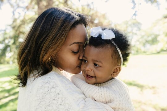 Affectionate mother kissing daughter in garden