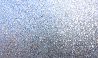 Obraz premium Ice crystals in detail on the window pane in winter. Abstract background of frosty water on the window glass. Texture of frosty patterns.