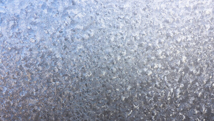 Ice crystals in detail on the window pane in winter. Abstract background of frosty water on the window glass. Texture of frosty patterns.