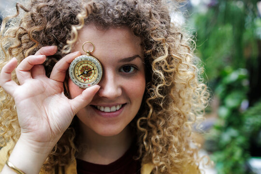 Young woman hiding face with navigational compass
