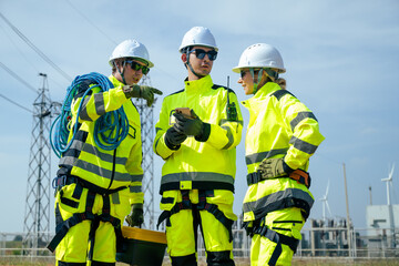 An engineer wearing safety gear closely inspects the base of a wind turbine in a renewable energy...