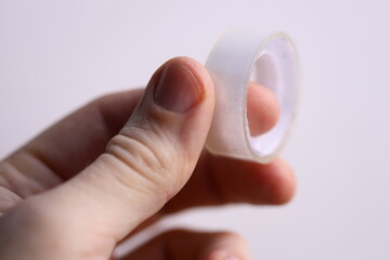 A person is holding a piece of tape in their hand, ready for use.