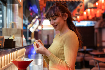 Smiling woman reading message of fortune cookie in restaurant