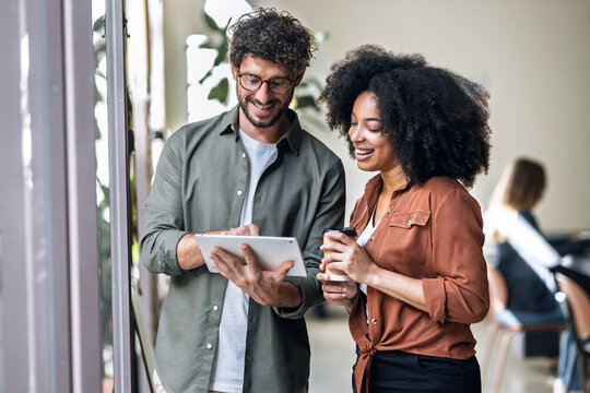 Smiling businessman discussing ideas with coworker through tablet PC in office