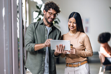 Smiling businessman explaining ideas to coworker through tablet PC in office