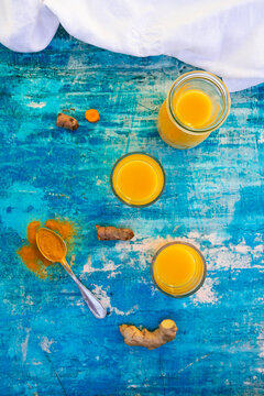 Ginger shot with turmeric and ginger root on a blue background