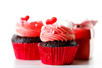 Chocolate cupcakes with pink cream and heart shaped sprinkles.