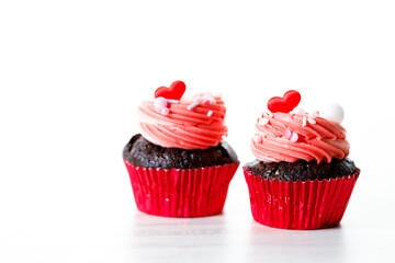 Chocolate cupcakes with pink cream and heart shaped sprinkles.