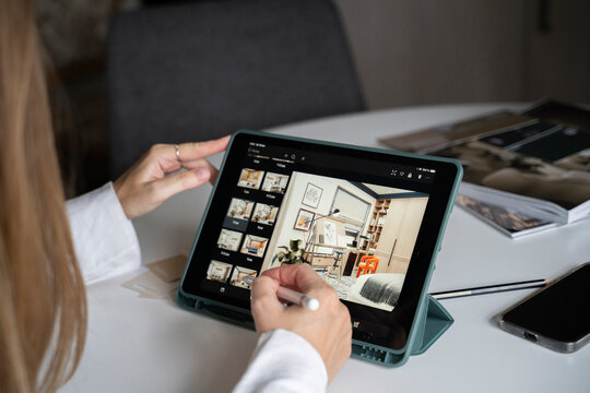 Hand of interior designer using digitized pen on tablet PC for designing floor plan