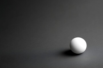 Single white sphere on dark surface, studio shot