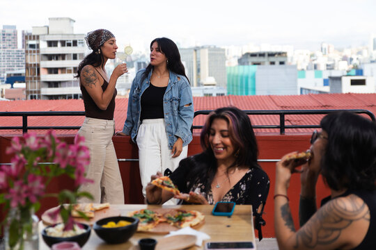 Women having pizza near friends standing on bar terrace
