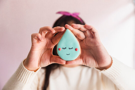 Young confectioner holding raindrop shaped cookie in hand