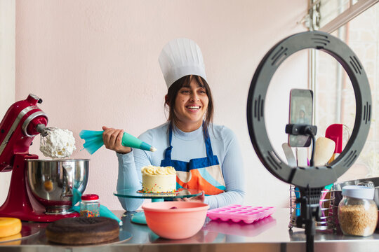 Happy influencer chef filming tutorial of making cake at home