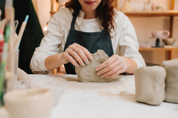 Potter is sculpting wet clay for ceramics products. Hands of a female potter making ceramic clay...