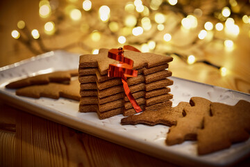 Christmas tree shaped gingerbread cookies in plate near lights