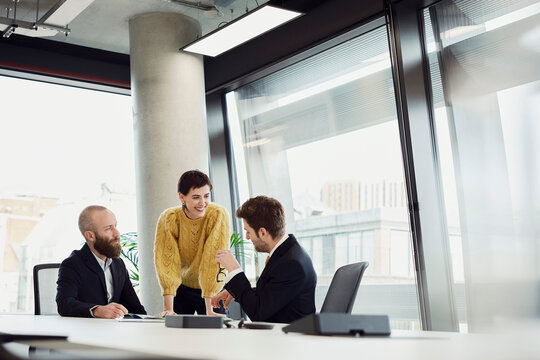 Colleagues discussing business strategy in a modern office boardroom